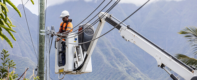 Technicien électricien travaillant sur un poteau électrique depuis une nacelle élévatrice